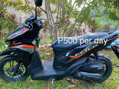 a motorcycle parked in the grass with a sign on it at Tiwi's Travellers Inn in Puerto Princesa City