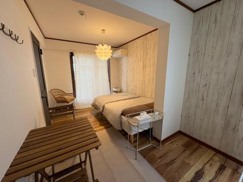 ein Schlafzimmer mit einem Bett und einem Tisch darin in der Unterkunft OSAKA DOSHIN HOUSE in Osaka