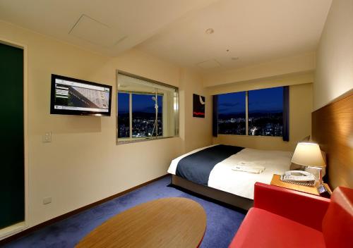 a hotel room with a bed and a desk with a phone at Oriental Hotel Hiroshima in Hiroshima