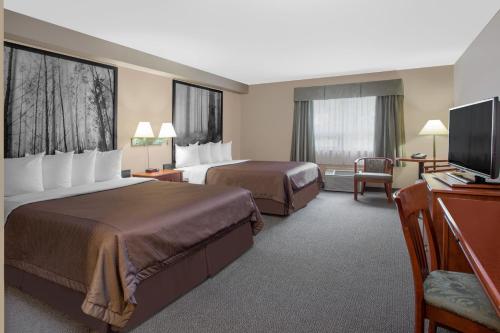 a hotel room with two beds and a flat screen tv at Super 8 by Wyndham Sault Ste Marie On in Sault Ste. Marie