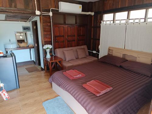a bedroom with a large bed and a couch at ม่วนใจ๋ปันสุข โฮมสเตย์แอนคาเฟ่ Muanjai punsuk homestay and cafe in Chom Thong