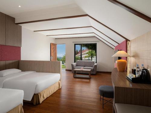 a bedroom with a bed and a couch and a desk at Hotel Niagara Parapat in Parapat