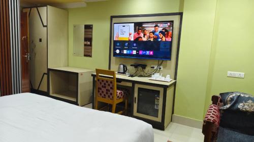 a room with a bed and a tv and a desk at Hotel Gokul Plaza Near Railway Station Bhubaneswar in Bhubaneshwar