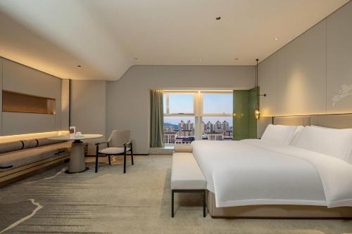 a bedroom with a large white bed and a window at Ramada By Wyndham Xiangyang Xiangcheng in Xiangyang