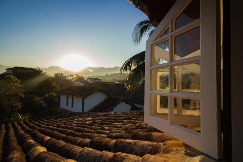 a window on a roof looking out at the sunset at Casa Simone Pousada in Paraty
