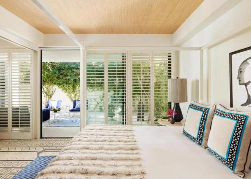 ein Schlafzimmer mit einem großen weißen Bett mit blauen Kissen in der Unterkunft Parker Palm Springs in Palm Springs