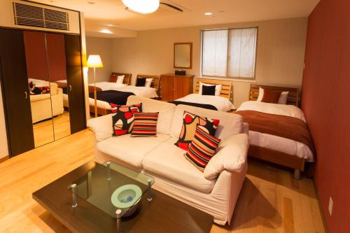 a living room with two beds and a couch with pillows at Seaside Hotel Twins Momochi in Fukuoka