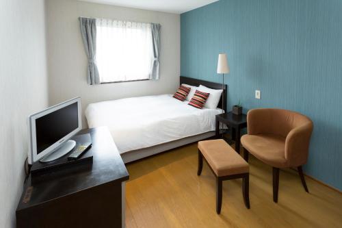 a bedroom with a bed and a desk with a computer at Seaside Hotel Twins Momochi in Fukuoka