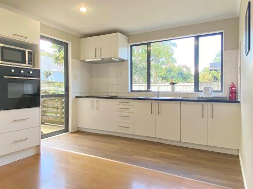 a kitchen with white cabinets and a large window at Kingsland Big Family Comfort House in Auckland