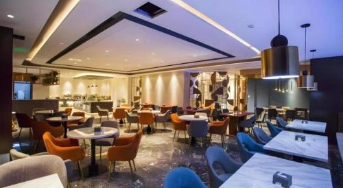 a restaurant with tables and chairs in a room at Yitel Collection Lianyungang High-speed Railway Station Suning Plaza in Hongmenxiang