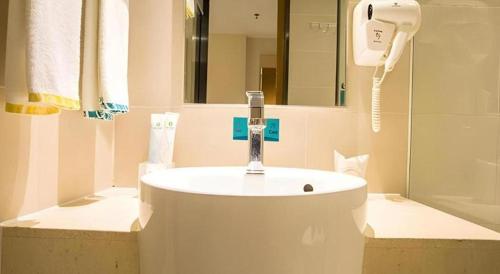 a bathroom with a white sink and a mirror at City Comfort Inn Hotel Nanning Nanhu Park Macun Metro Station in Nanning