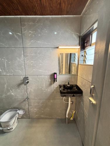 a bathroom with a sink and a mirror at Indraprastha Cottage in Alibaug