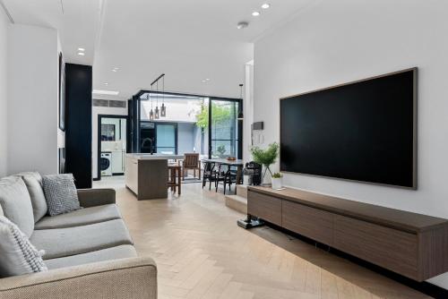 a living room with a large flat screen tv on a wall at Spacious Family-Friendly 5-BR Home in Glebe in Sydney