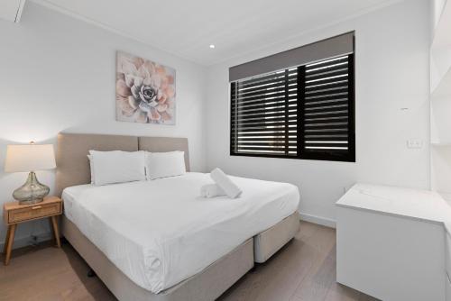 a white bedroom with a bed and a window at Spacious Family-Friendly 5-BR Home in Glebe in Sydney