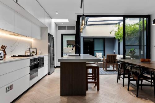 a kitchen with white cabinets and a dining room with a table at Spacious Family-Friendly 5-BR Home in Glebe in Sydney