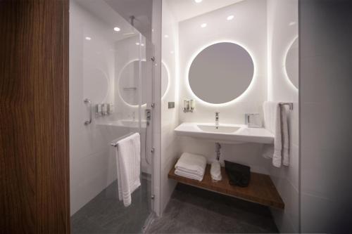 een witte badkamer met een wastafel en een spiegel bij Hampton By Hilton Denizli in Denizli