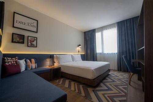 een hotelkamer met een bed en een bank bij Hampton By Hilton Denizli in Denizli