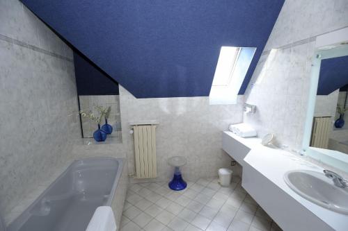 ein Badezimmer mit einer Badewanne, einem Waschbecken und einer blauen Decke in der Unterkunft Le Relais De La Poste in Neuvéglise