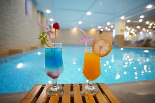 two cocktails sitting on a table next to a swimming pool at Ramada by Wyndham Islamabad in Islamabad