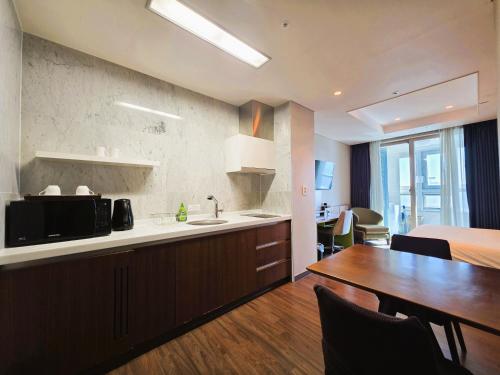 a kitchen and dining room with a table and a microwave at W Residence Hotel in Busan