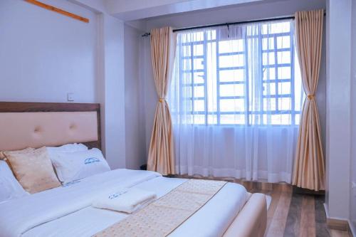 Havana Cottages-Hyrax Deluxe Master في ناكورو: غرفة نوم بها سرير ونافذة كبيرة