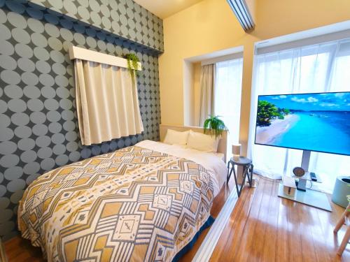 a bedroom with a bed and a flat screen tv at Nishiki Stay Takamatsu101 in Takamatsu