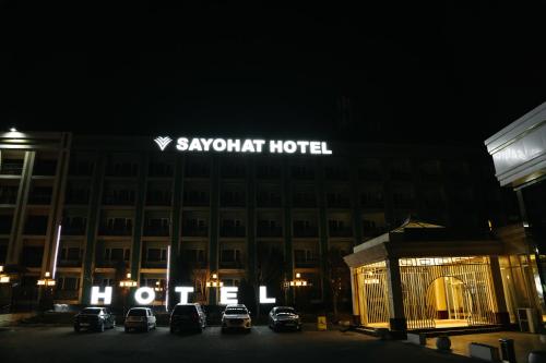 a large hotel with cars parked in front of it at night at Sayohat Hotel in Tashkent