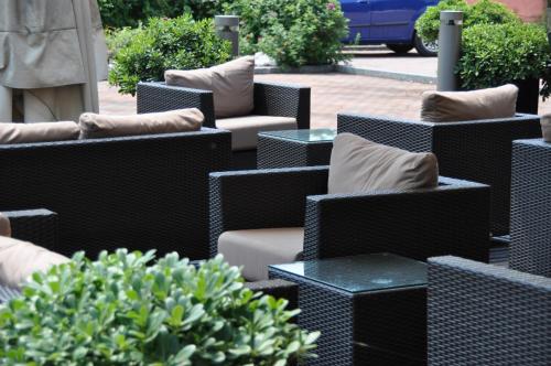 a row of wicker chairs and tables with pillows at First Hotel Malpensa in Case Nuove
