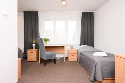 a bedroom with a bed and a desk and a window at Hotel Dom Polonii in Ostróda
