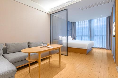a living room with a couch and a table and a bed at JI Hotel Chengdu High Tech in Chengdu