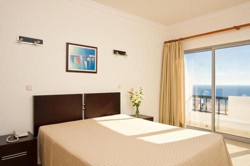 a bedroom with a large bed and a large window at Silmar in Albufeira