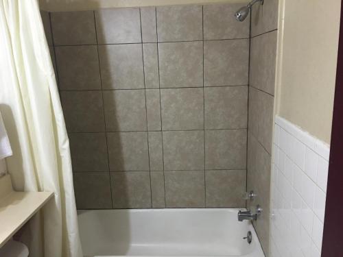 a bathroom with a shower with a white tub at Best Value Inn Motel Sandusky in Marianna