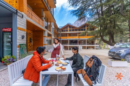 Zostel Kasol, Main Market في كاسول: مجموعة من الأشخاص يجلسون على طاولة ويتناولون الطعام