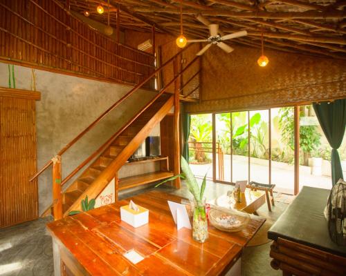 ein Wohnzimmer mit einem Holztisch und einer Treppe in der Unterkunft Happiness Native Villa in El Nido