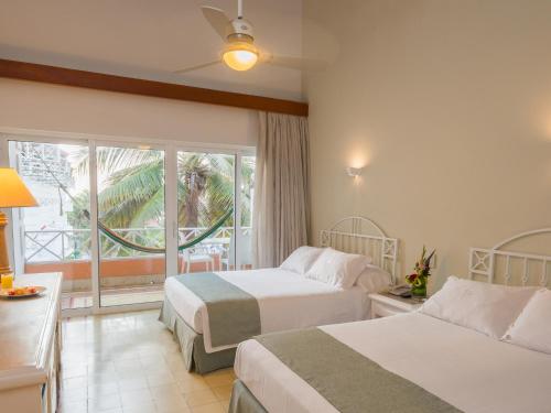 a hotel room with two beds and a window at Hotel Las Americas Casa de Playa in Cartagena de Indias