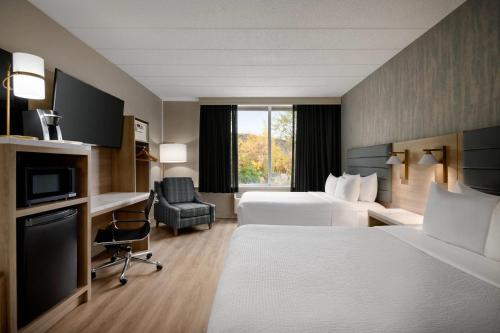 ein Hotelzimmer mit zwei Betten und einem Schreibtisch in der Unterkunft Radisson Hotel Montreal Airport in Saint-Laurent
