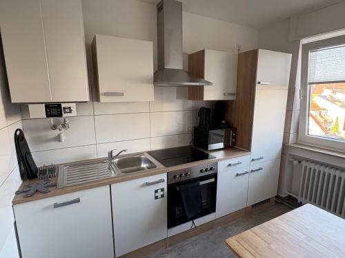 Altstadtperle Ettlingen mit Smart TV und WLAN في إيتلينغن: مطبخ بخزائن بيضاء ومغسلة