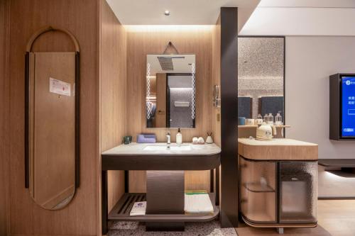 ein Badezimmer mit Waschbecken und Spiegel in der Unterkunft Changzhou Railway Station Qingguoxiang Manxin Hotel in Changzhou