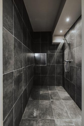 a bathroom with a shower with black tiles at The Villa Amalia in Spartos