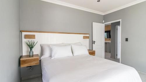 a bedroom with a white bed with a wooden night stand at Skobbejak in Paternoster
