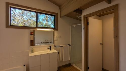 a bathroom with a sink and a mirror and a window at Wonderland Cottages in Halls Gap
