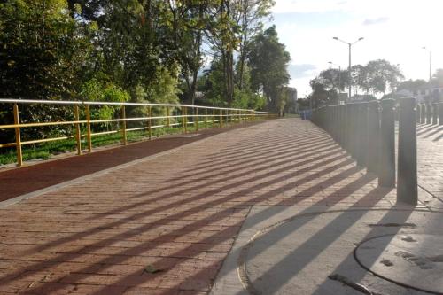 a brick road with a fence and trees on it at Casa Posada Amelia in Bogotá