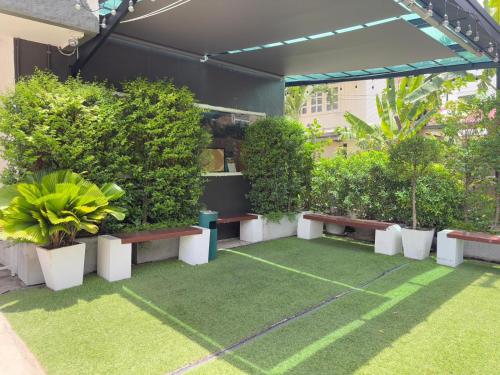 a patio with benches and plants and grass at OYO 75446 Travis Inthamara 49 in Bangkok