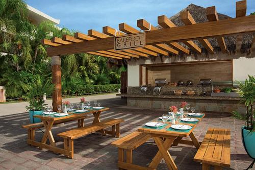 
a patio area with a table, chairs, and tables with umbrellas at Dreams Sapphire Resort & Spa in Puerto Morelos
