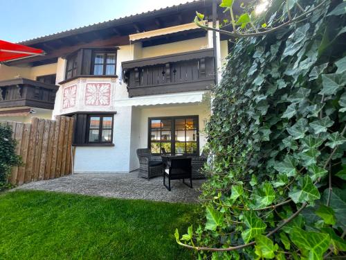 a ivy covered building with a table in a yard at Apartmenthaus Der Johanneshof - tolle Lage nah am See in Schliersee