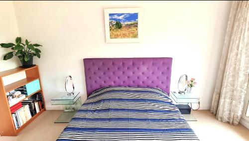 a bed with a purple headboard in a bedroom at Casalionel Le calme à 25 min de Paris in Le Vésinet