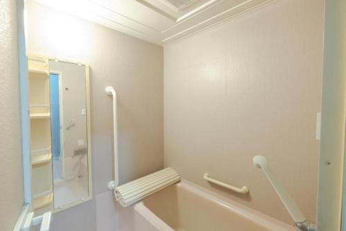 a white bathroom with a tub and a mirror at B cycle ダブルルーム in Biei