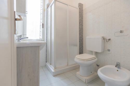 a white bathroom with a toilet and a sink at Appartamento Lentisco Centro by ElbaSummer in Marina di Campo