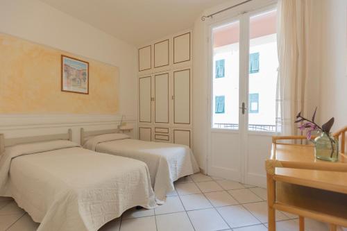 a bedroom with two beds and a window at Appartamento Lentisco Centro by ElbaSummer in Marina di Campo