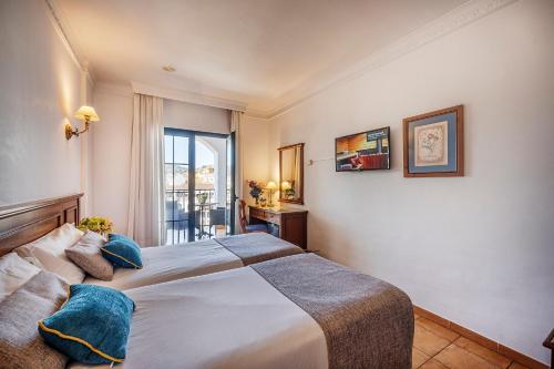 a bedroom with a large bed with blue pillows at Hotel Villa Frigiliana in Frigiliana